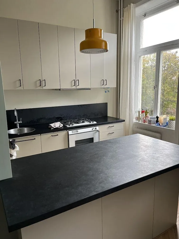 Närbild på köksbänkskiva i Nero Assoluto granit med mörk halvö, stänkskydd och vask i Stockholm.