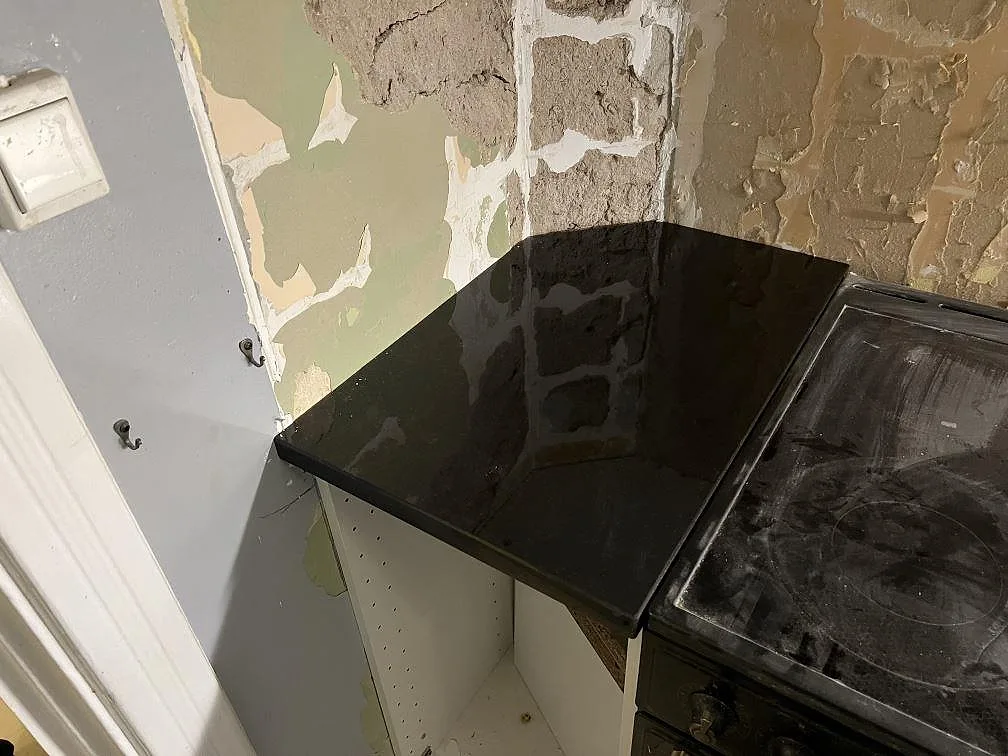 Detalj av polerad Nero Assoluto i svart granit vid spisen i ett kök under montering i Stockholm.