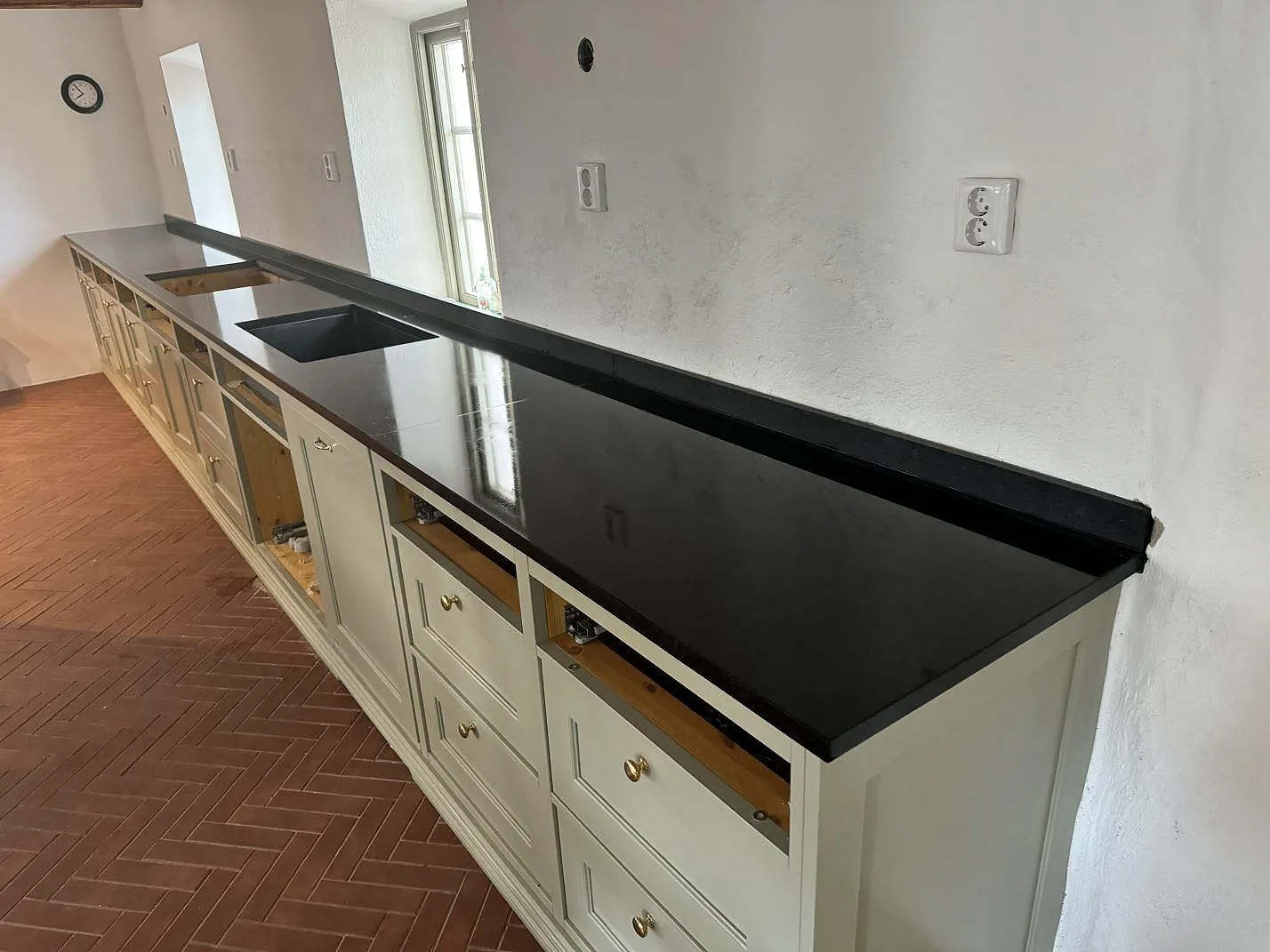 Köksbänkskiva i Nero Assoluto granit, matt, med underlimmad diskho och uppvikt stänkkant i ett kök i Svedala.