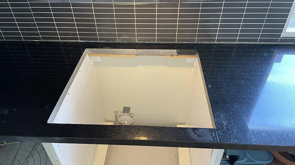 Detalj av polerad Nero Assoluto köksbänkskiva i granit över ett öppet bänkskåp i Svedala.