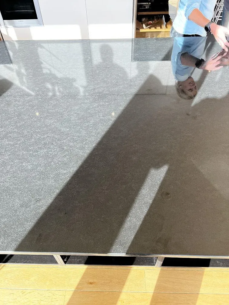 Reflektioner i polerad Nero Assoluto granit på en mörk köksö under montering i Torslanda.