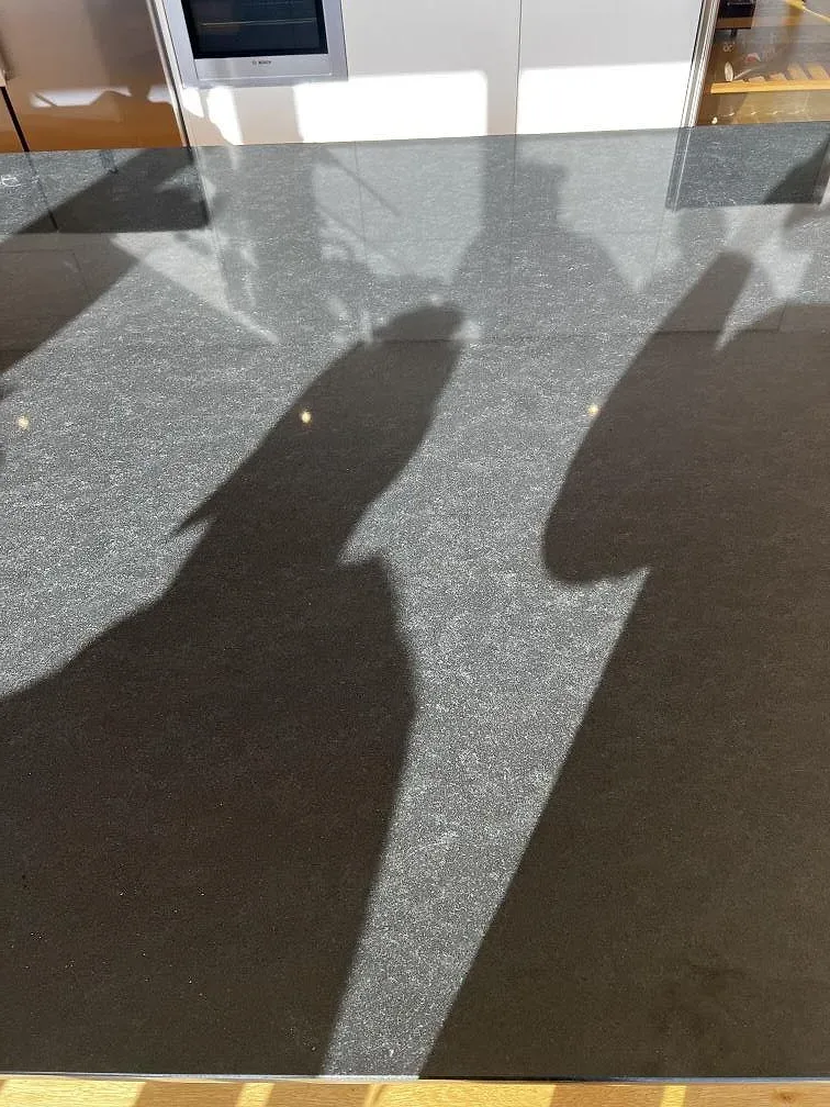 Närbild av ljusspel över polerad Nero Assoluto granit på köksön i Torslanda.