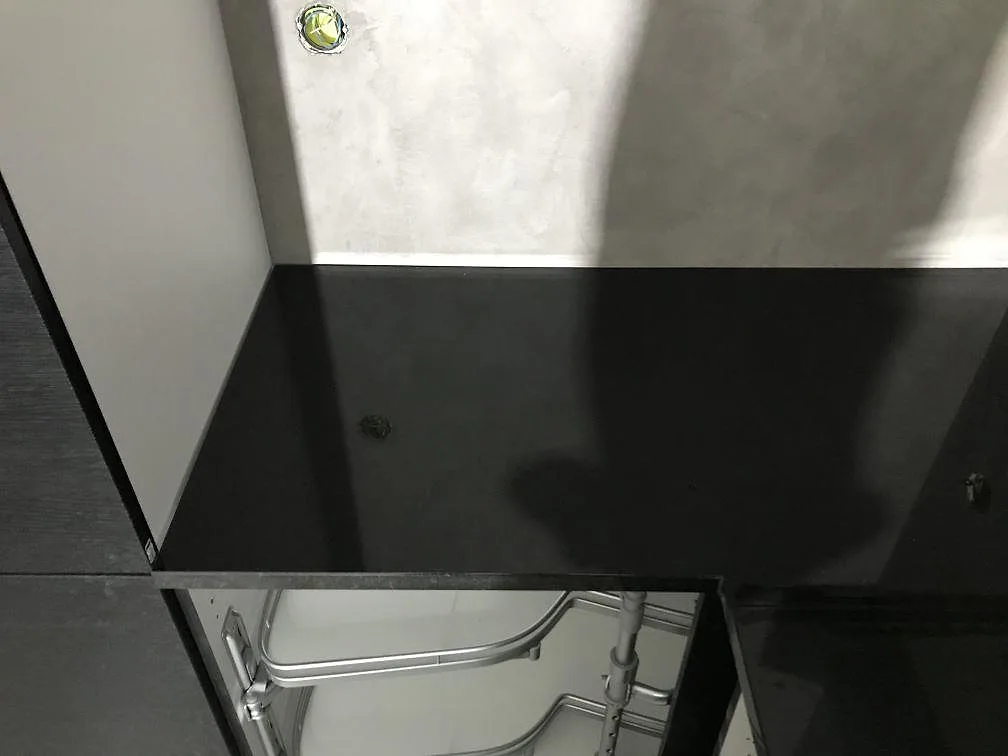 Polerad svart bänkskiva i Nero Assoluto granit längs köksvägg med öppna stommar i Torsö.