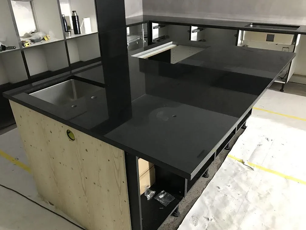Köksö och väggbänkar i polerad svart Nero Assoluto granit i ett kök under montering i Torsö.
