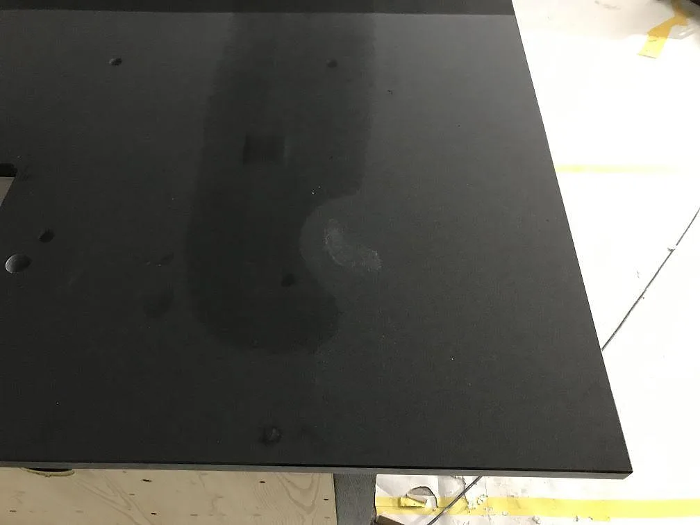 Detalj av blank svart Nero Assoluto granit på köksö under montering i Torsö.