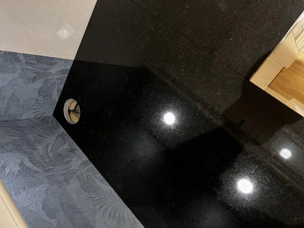 Polerad svart Nero Assoluto granitbänkskiva med blank yta och uttag för blandare i ett kök i Träslövsläge.