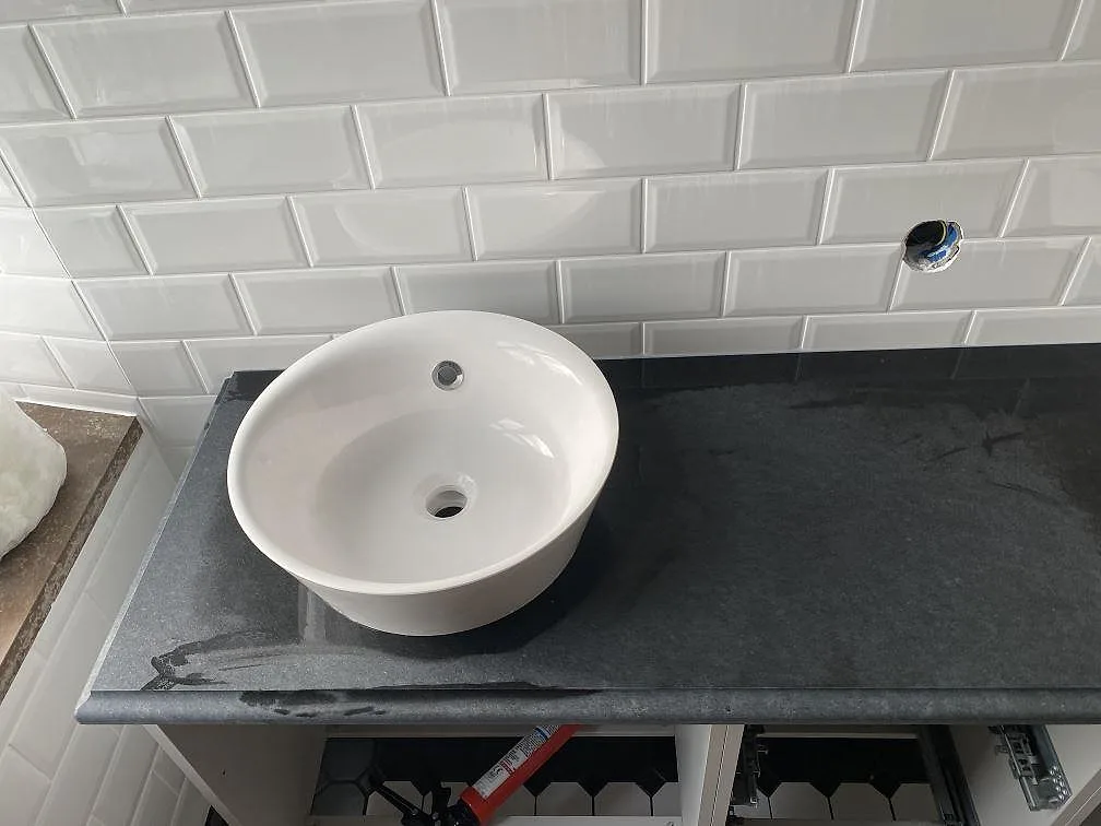 Närbild på matt Nero Assoluto granit med ovanpåliggande tvättställ och mörk stenyta i ett badrum i trelleborg.