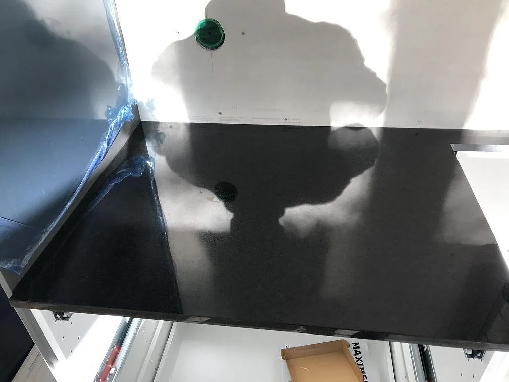 Spegelblank yta på svart polerad Nero Assoluto granitbänkskiva med borrat blandarhål i ett kök i Trensum.
