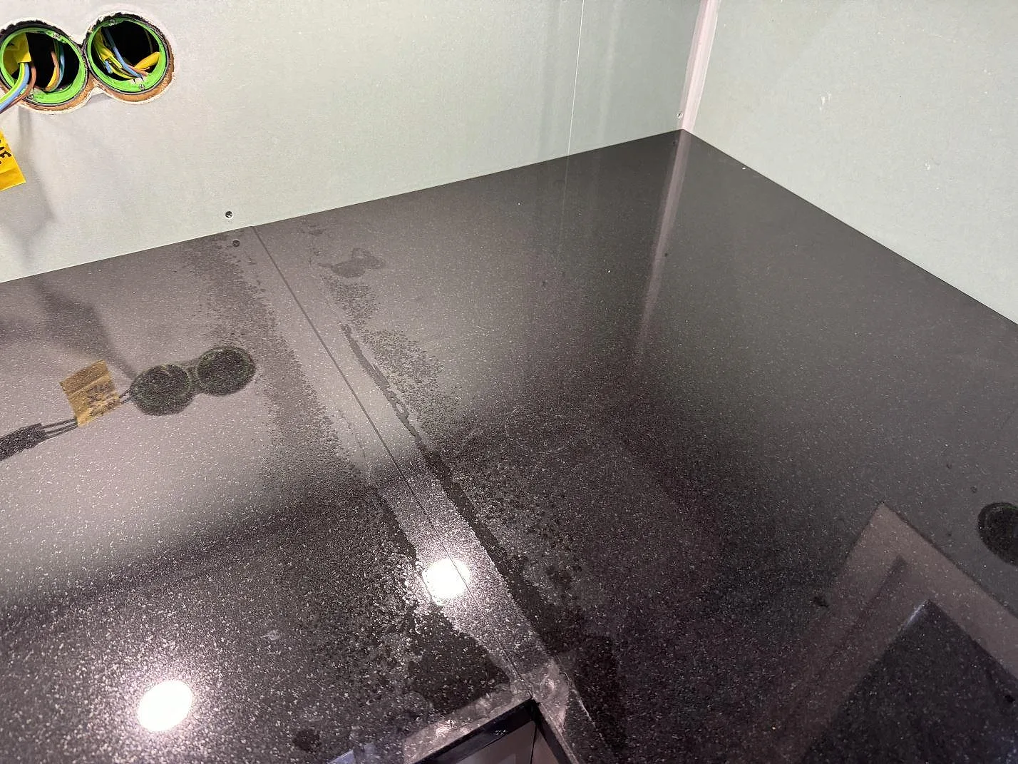 Detalj av hörn i L-formad Nero Assoluto granitbänkskiva med blank polerad yta i Trollhättan.