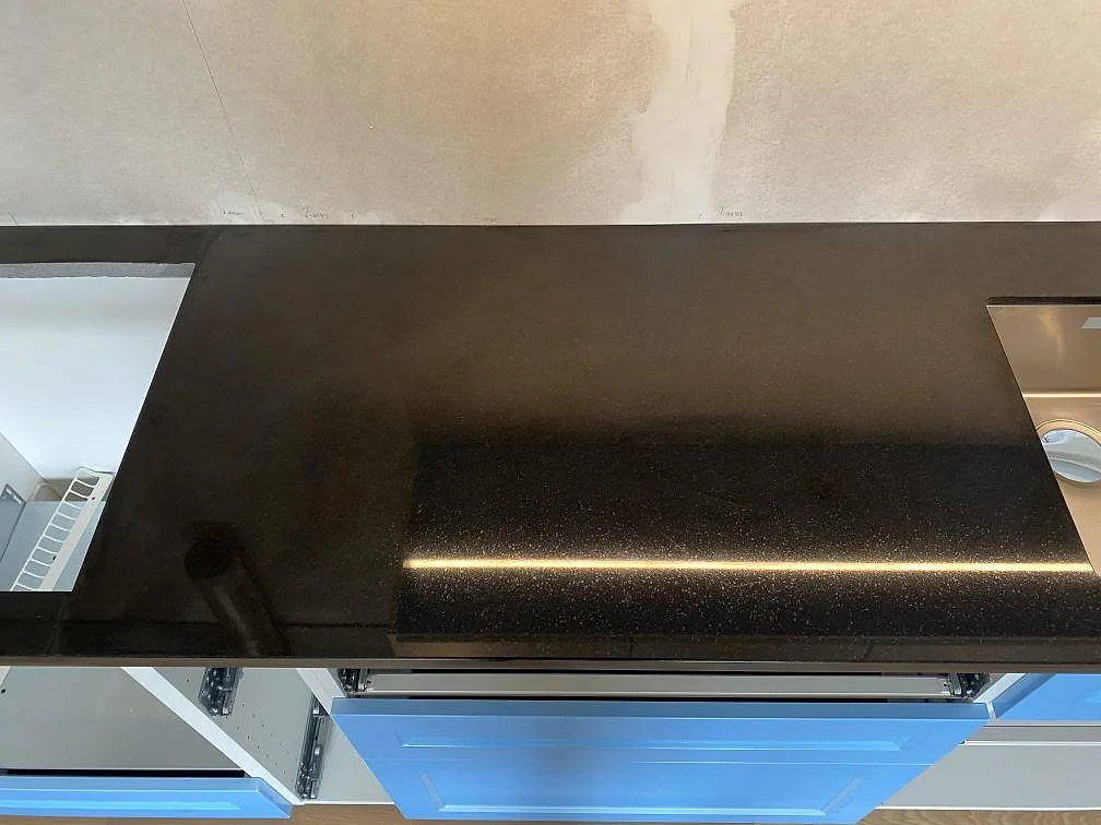 Blank svart Nero Assoluto granit som arbetsyta mellan urtag och skåpsfront i ett kök i Vänersborg.