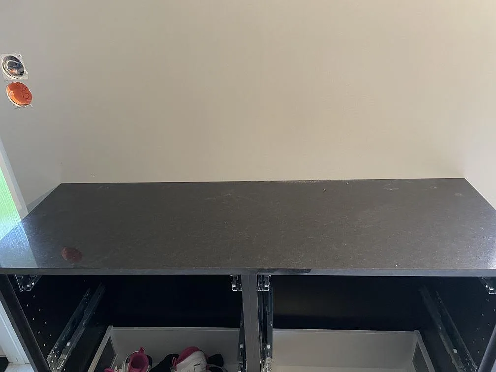 Detalj av polerad Nero Assoluto granit som bänkskiva på svart stomme under montering i Väring.
