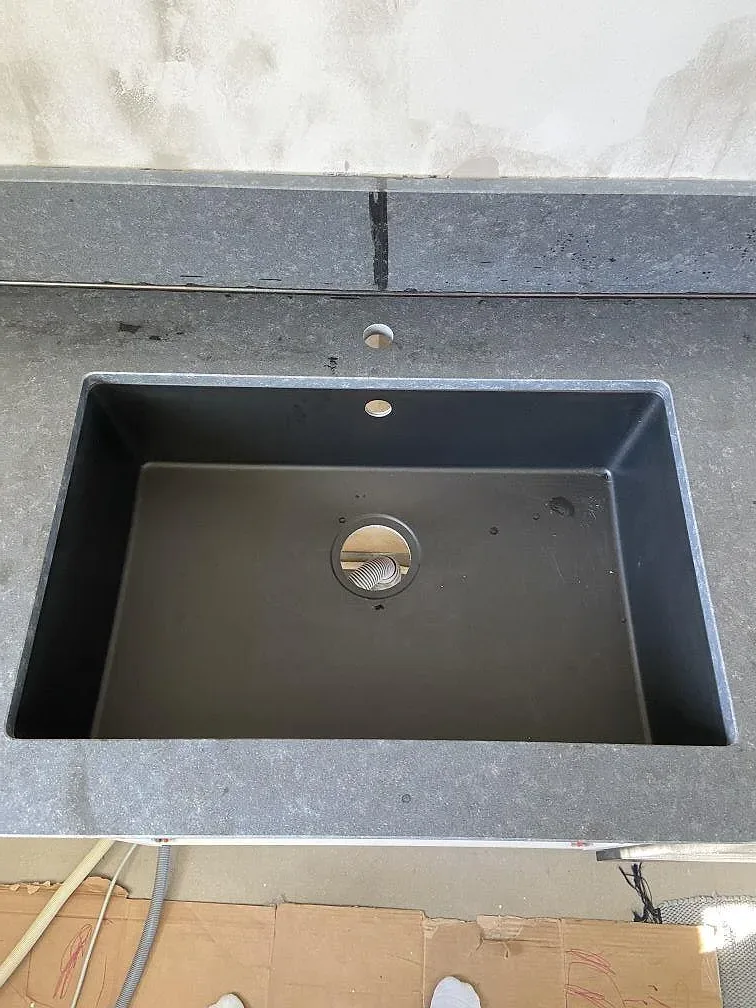 Närbild på underlimmad diskho i svart komposit infälld i matt svart granit i ett kök i Västra Frölunda.