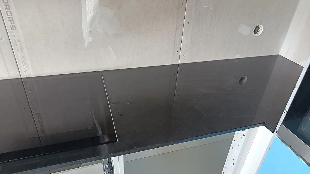 Rak köksbänkskiva i polerad Nero Assoluto granit med inbyggd häll under montering i Västra frölunda.