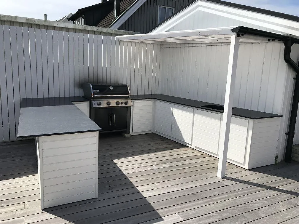 Köksbänkskiva i svart Nero Assoluto granit, matt, i ett utomhuskök på altan med köksö och grill i Vellinge.