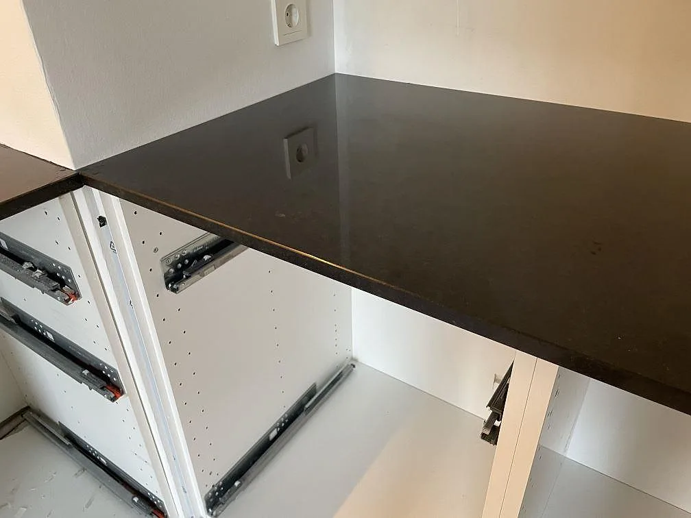 Polerad svart granitbänkskiva i Nero Assoluto monterad över öppna vita köksstommar i Vellinge.