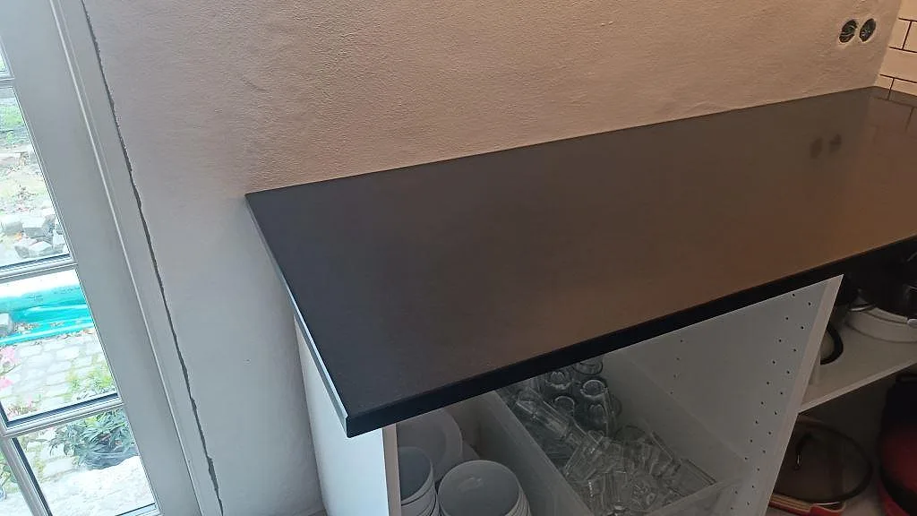 Närbild av vänster bänkskiva i matt Nero Assoluto granit över öppna köksstommar i Ystad.