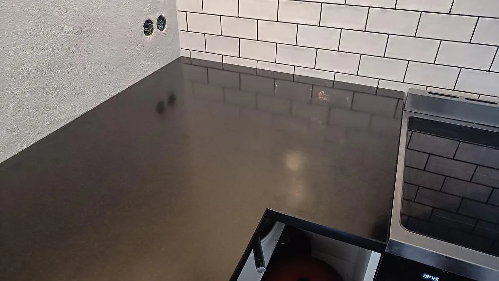 Detalj av matt Nero Assoluto granit intill fristående spis och vitt kakel i kök i Ystad.