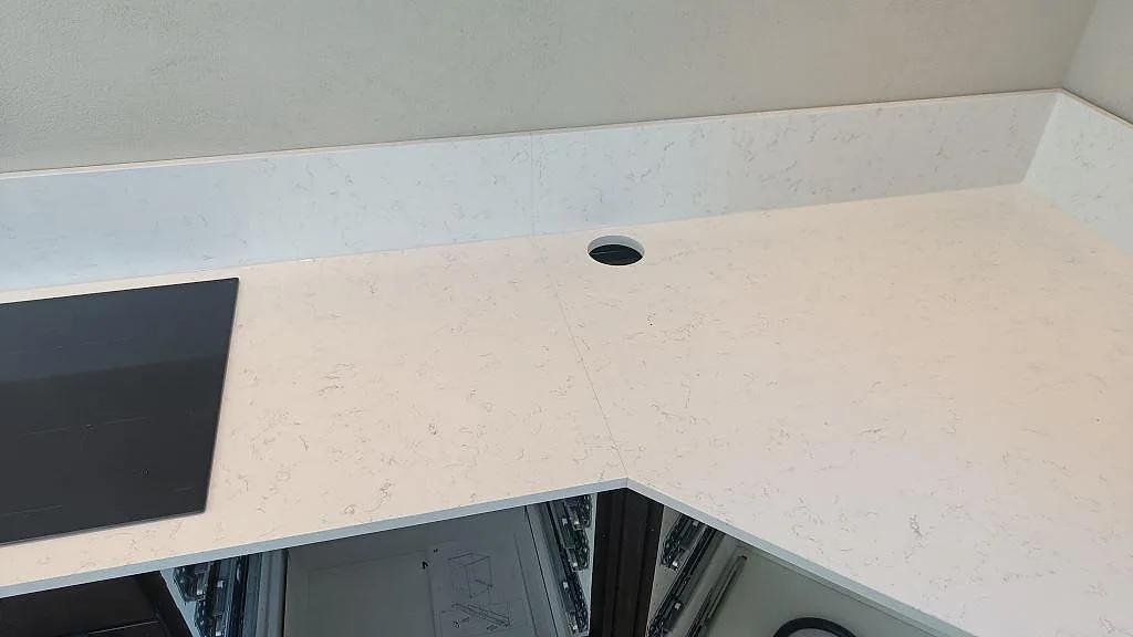 Köksbänkskiva i vit Technistone Noble Areti Bianco med blandarhål och infälld häll i ett kök i Torslanda.