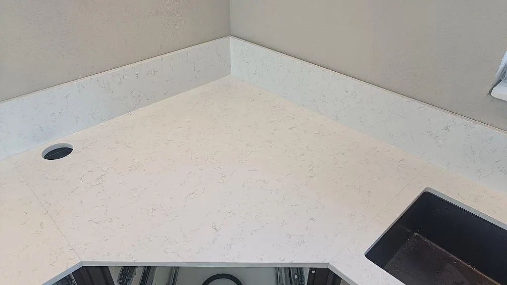 Köksbänkskiva i vit Technistone Noble Areti Bianco med underlimmad diskho och borrat blandarhål i ett kök i Torslanda.