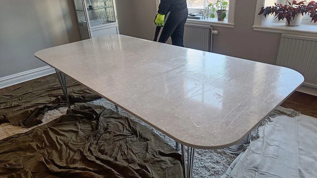 Bordsskiva i Technistone Noble Olympos Mist, ljus vit kvartskomposit med dimgrå ådring, polerad yta på förkromade ben i ett matrum i Malmö.