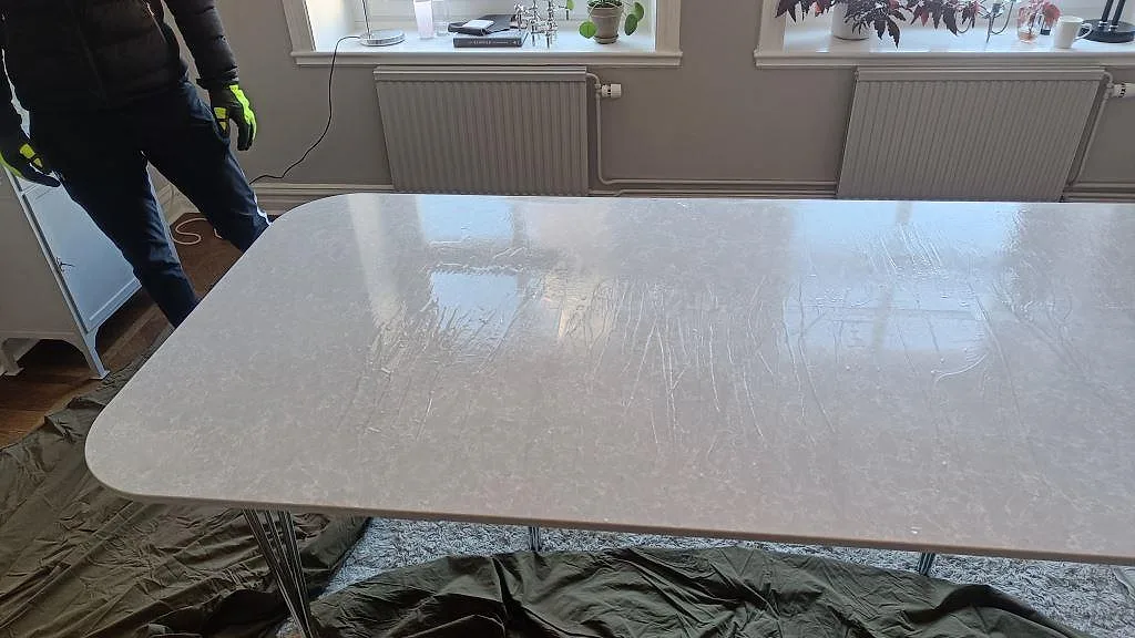 Polerad bordsskiva i Technistone Noble Olympos Mist med mjuk grå ådring i ett ljust matrum med fönster, Malmö.