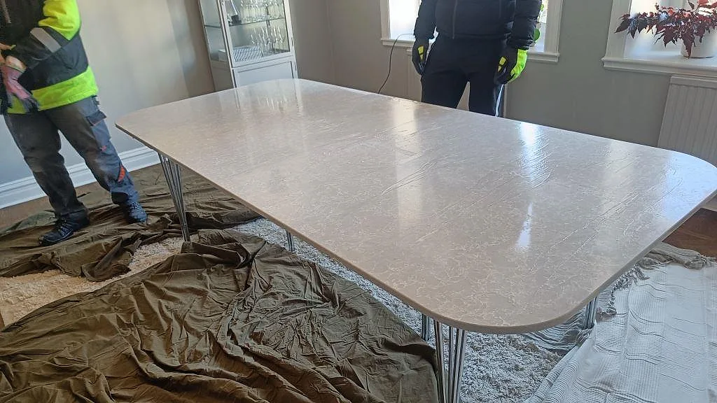 Matbordsskiva i vit Technistone Noble Olympos Mist, polerad komposit, nyligen monterad på smala metallben under installationen i ett hem i Malmö.