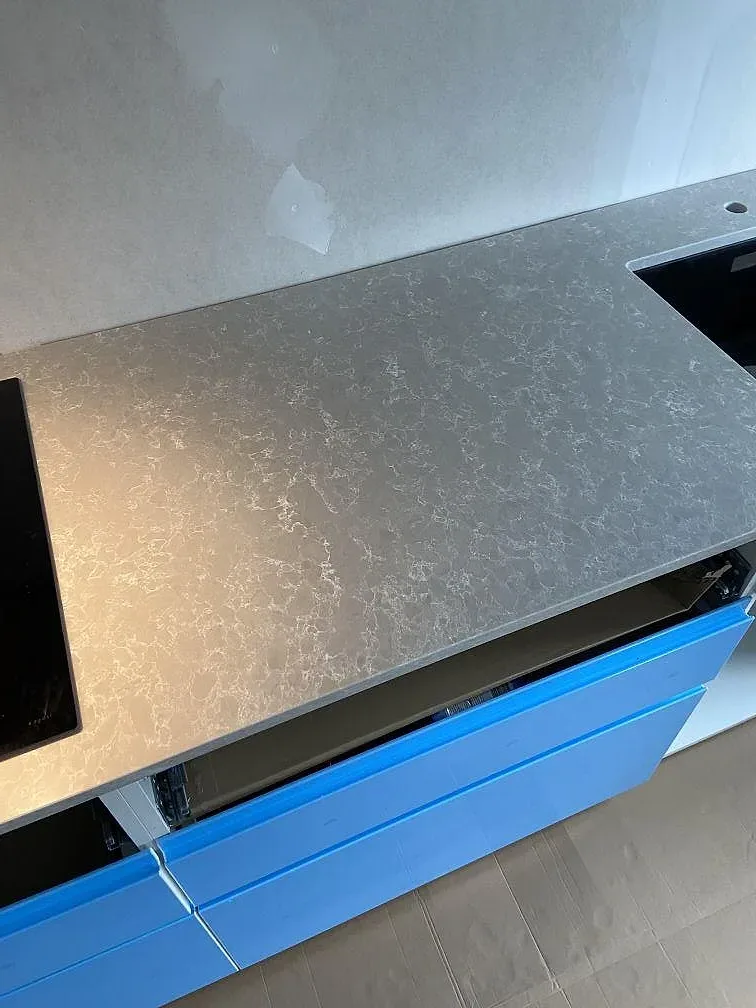 Köksö i grå Technistone Noble Olympos Mist, polerad, med utskuren häll och tydlig ådring i ett kök i Svedala.