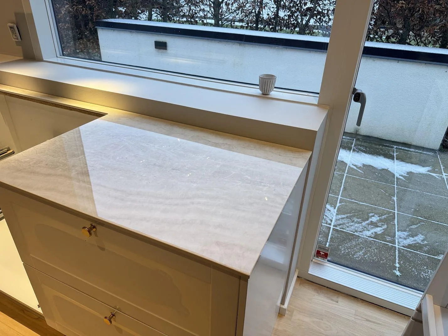 Köksbänkskiva i polerad keramik Nuovo Corso Taj Mahal med djup matchande fönsterbänk i samma sten vid fönstret i ett kök i Aalborg.