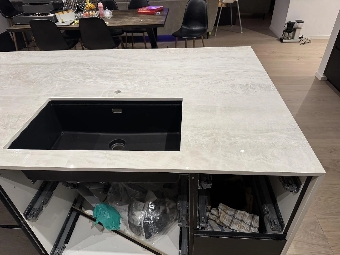 Närbild på svart diskho och polerad Nuovo Corso Taj Mahal köksbänkskiva, med blank ljus keramikyta i ett kök i Gantofta.