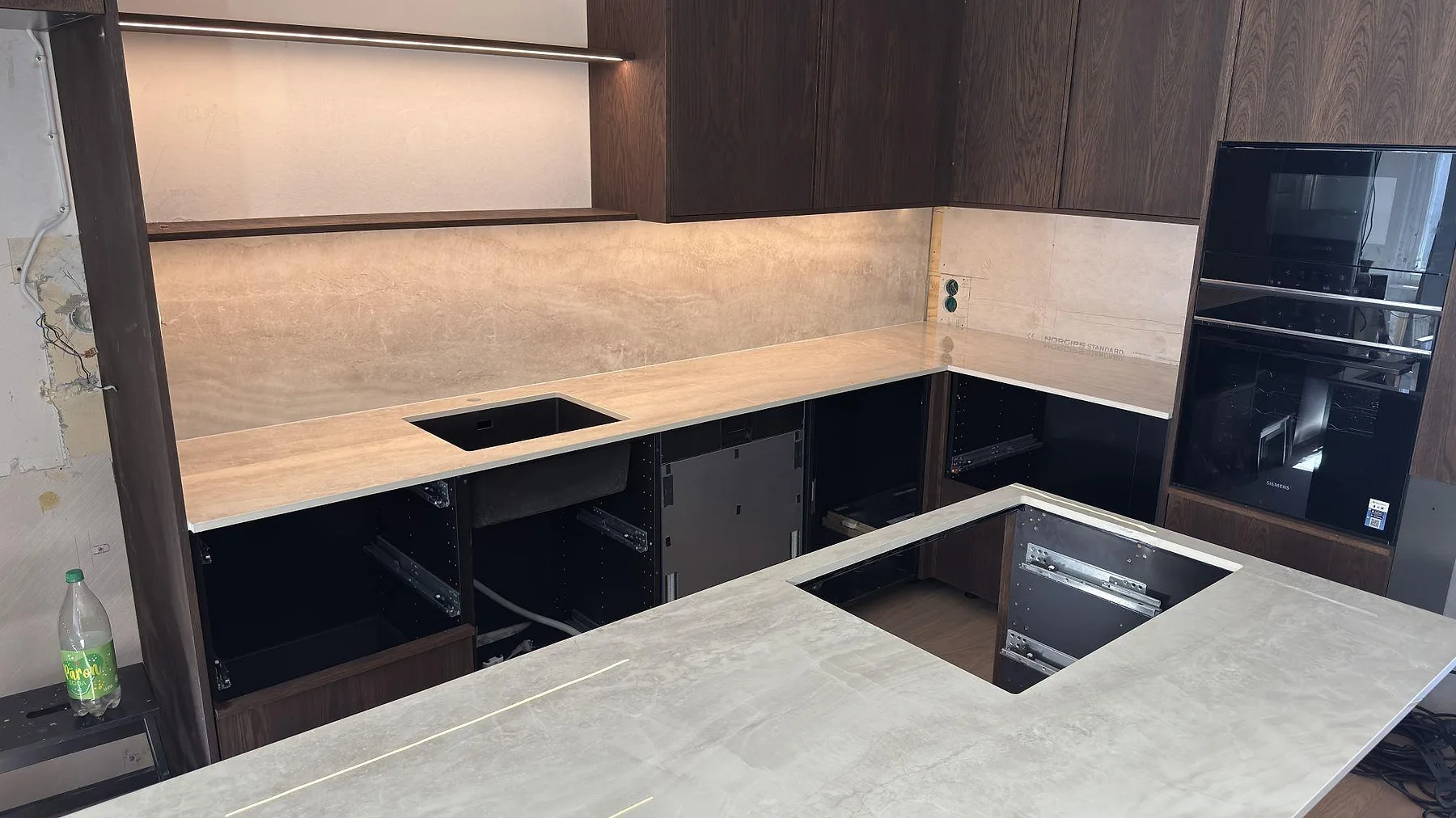 Köksbänkskiva och hörnrad i beige keramik Nuovo Corso Taj Mahal med stänkvägg och urtag för diskho, mörka träskåp, i ett kök i Nacka.