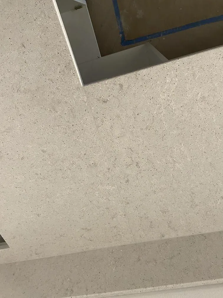Ovanljus över bänkytan i vit Quarella Bianco Savoia kvartskomposit med fin grå spräcklighet i ett kök under montering i Blekinge.