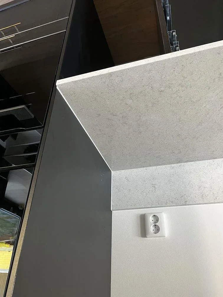 Hörndetalj av Quarella Bianco Savoia bänkskiva med uppvikt stänkkant i ett kök i Gantofta.