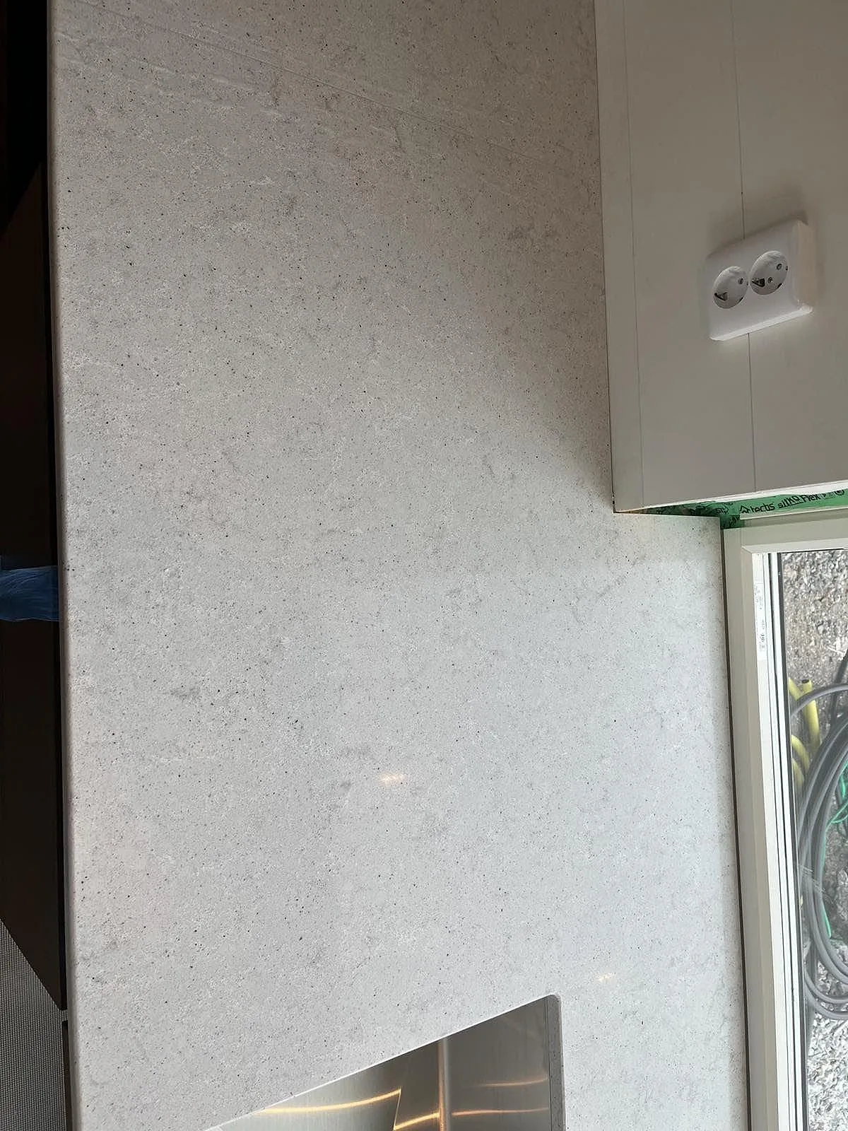 Vit Quarella Bianco Savoia-bänkskiva mot vägg med eluttag i ett kök under inredning i Grebbestad.