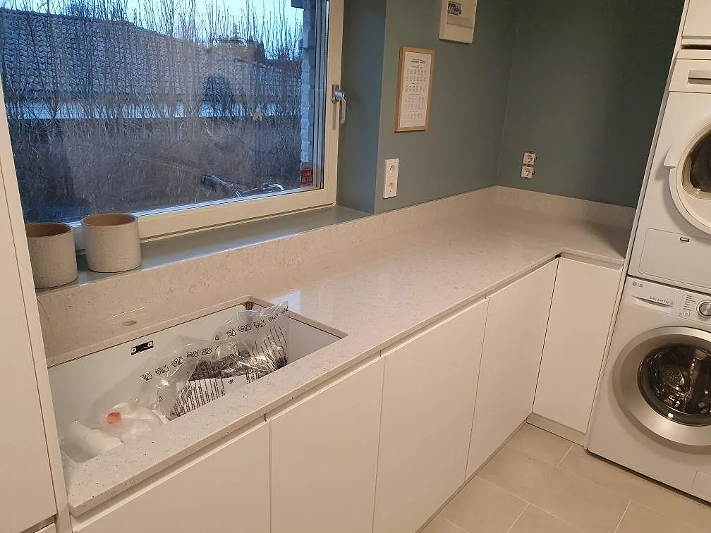 L-formad bänkskiva i Quarella Bianco Savoia med fönsterbänk i samma komposit, fotad under montering i ett grovkök i Hässelby.