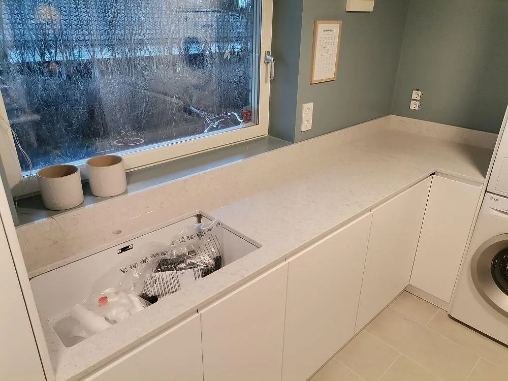 Bänkskiva i Quarella Bianco Savoia med underlimmad ho och matchande fönsterbänk, fotad under montering i Hässelby.