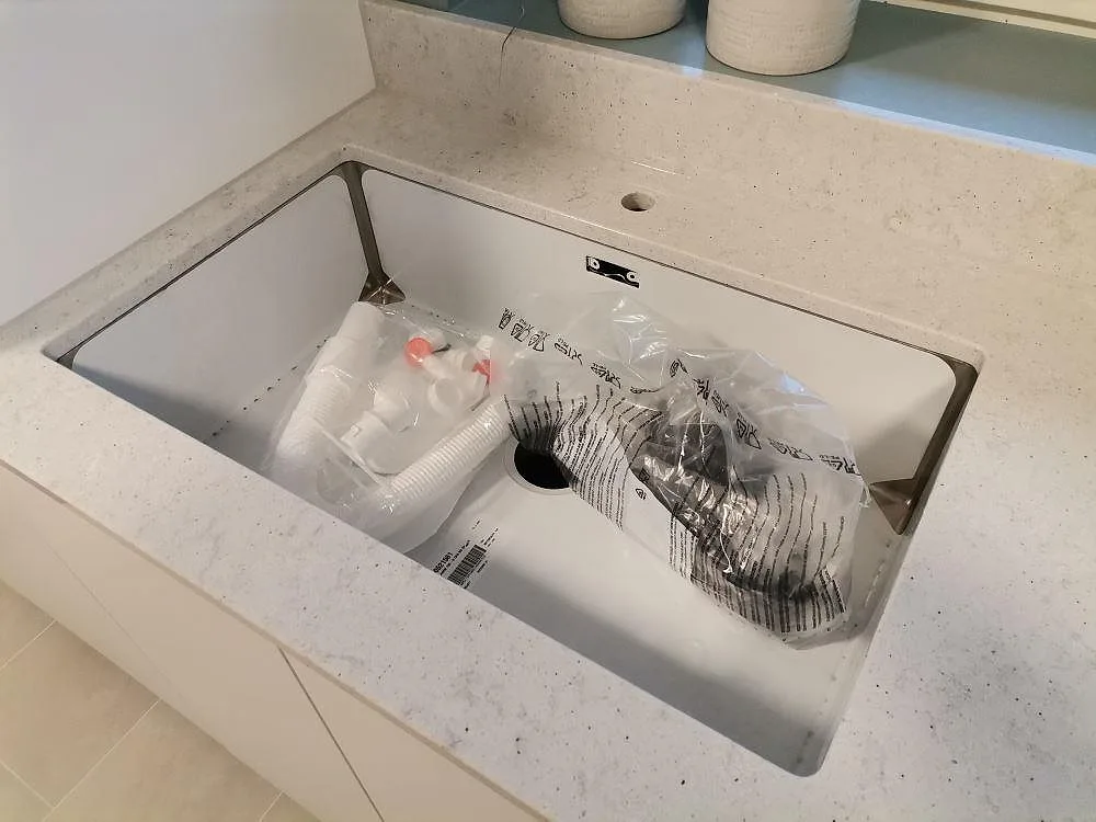 Underlimmad ho i en bänkskiva av Quarella Bianco Savoia, sedd uppifrån, i ett tvättrum i Hässelby.