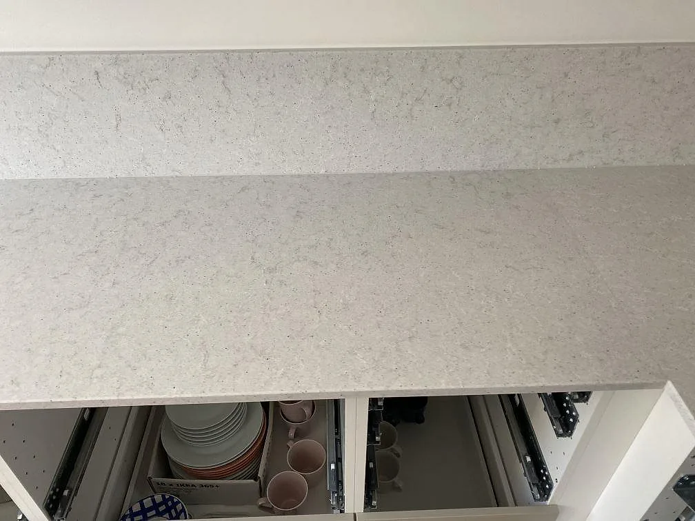 Ovanifrån av vit polerad Quarella Bianco Savoia köksbänkskiva i komposit i ett kök i Helsingborg.