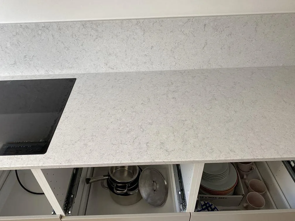 Vit Quarella Bianco Savoia kompositbänkskiva med svart induktionshäll längs köksväggen i Helsingborg.
