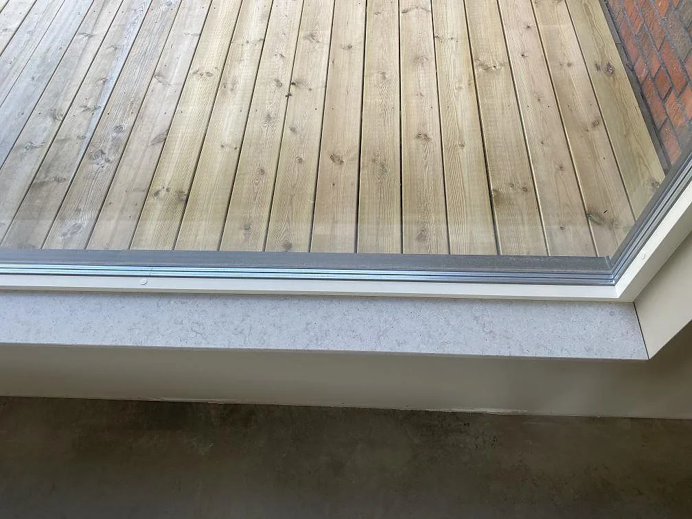 Fönsterbänk i Quarella Bianco Savoia, komposit, vid ett fönster mot träaltan i ett kök i Kungsbacka.