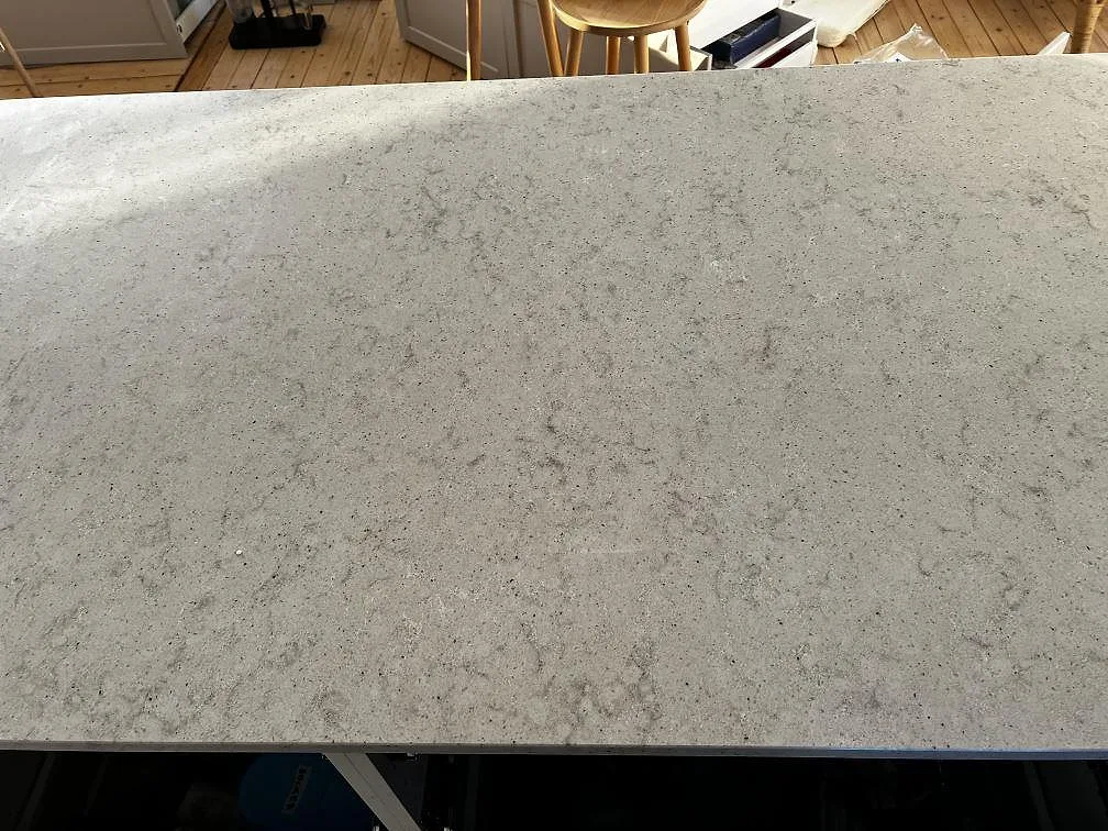 Ytnära bild av polerad Quarella Bianco Savoia kvartskomposit med fin grå spräcklighet i ett kök i Lomma.
