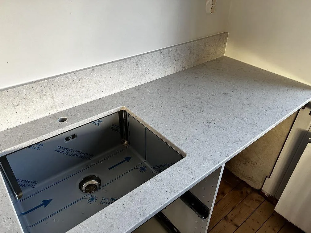 Köksbänkskiva i Quarella Bianco Savoia med underlimmad rostfri diskho och låg stänkkant i ett kök i Lomma.