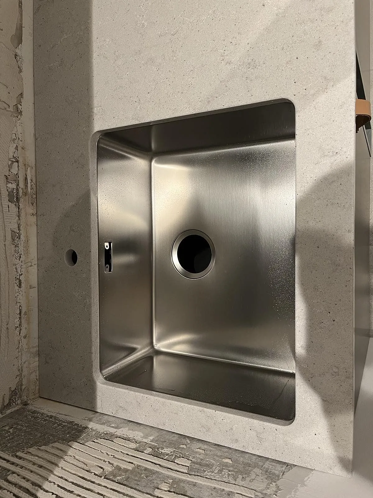 Underlimmad rostfri diskho infälld i vit Quarella Bianco Savoia köksbänkskiva i komposit, Malmö, under montering.