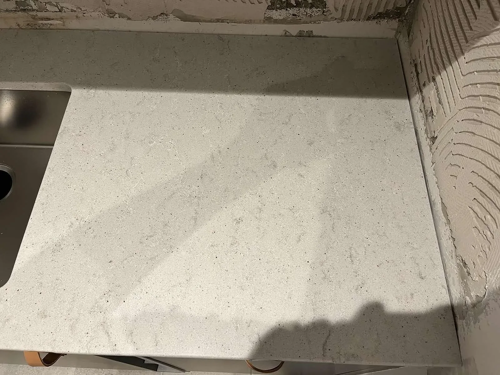 Vit Quarella Bianco Savoia kompositskiva monterad som stänkskydd vid köksbänken i Malmö, under montering.