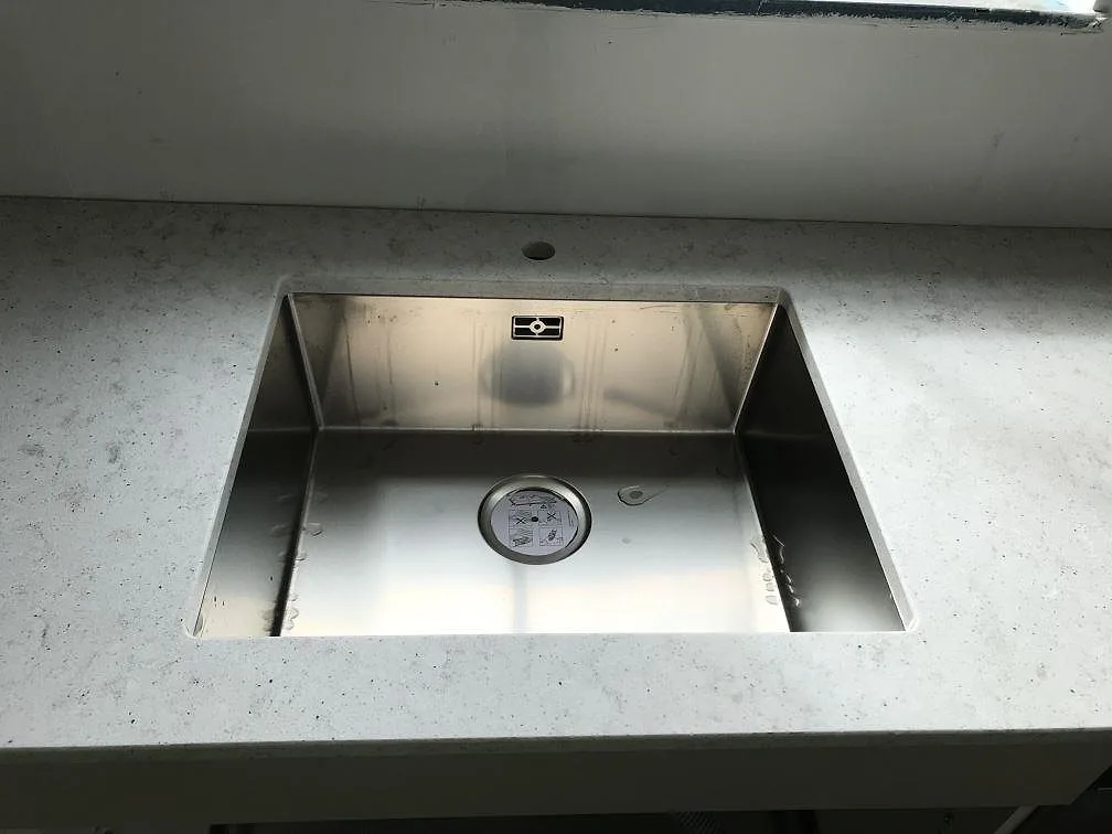 Underlimmad rostfri diskho infälld i polerad köksbänkskiva av Quarella Bianco Savoia i Östra Grevie.