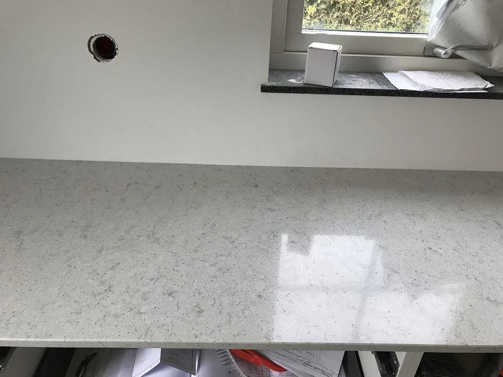 Köksbänkskiva i Quarella Bianco Savoia som löper runt hörnet ovanpå köksstommarna i Östra Grevie.