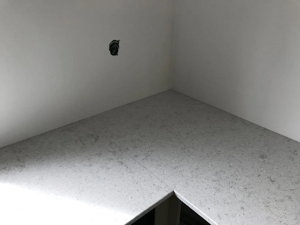 Hörnlösning i köksbänkskiva av Quarella Bianco Savoia, ljus kvartskomposit med polerad yta i Östra Grevie.