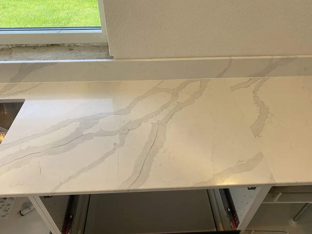 Vit Quarella Bianco Venere köksbänkskiva med mjuk grå ådring vid fönster i ett kök i Påarp.