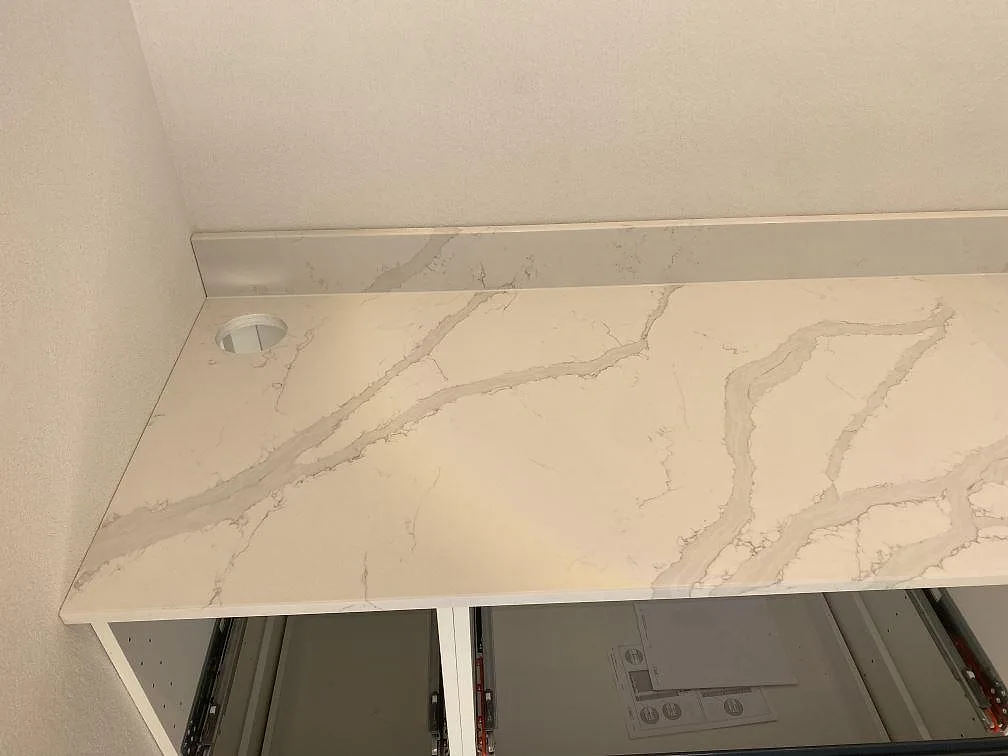 Köksbänkskiva i polerad Quarella Bianco Venere komposit med urtag för köksblandare i ett kök i Påarp.