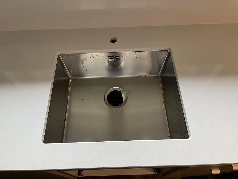 Underlimmad rostfri diskho i en vit Quarella Blanco Sal köksbänkskiva, polerad, i Tjörnarp.