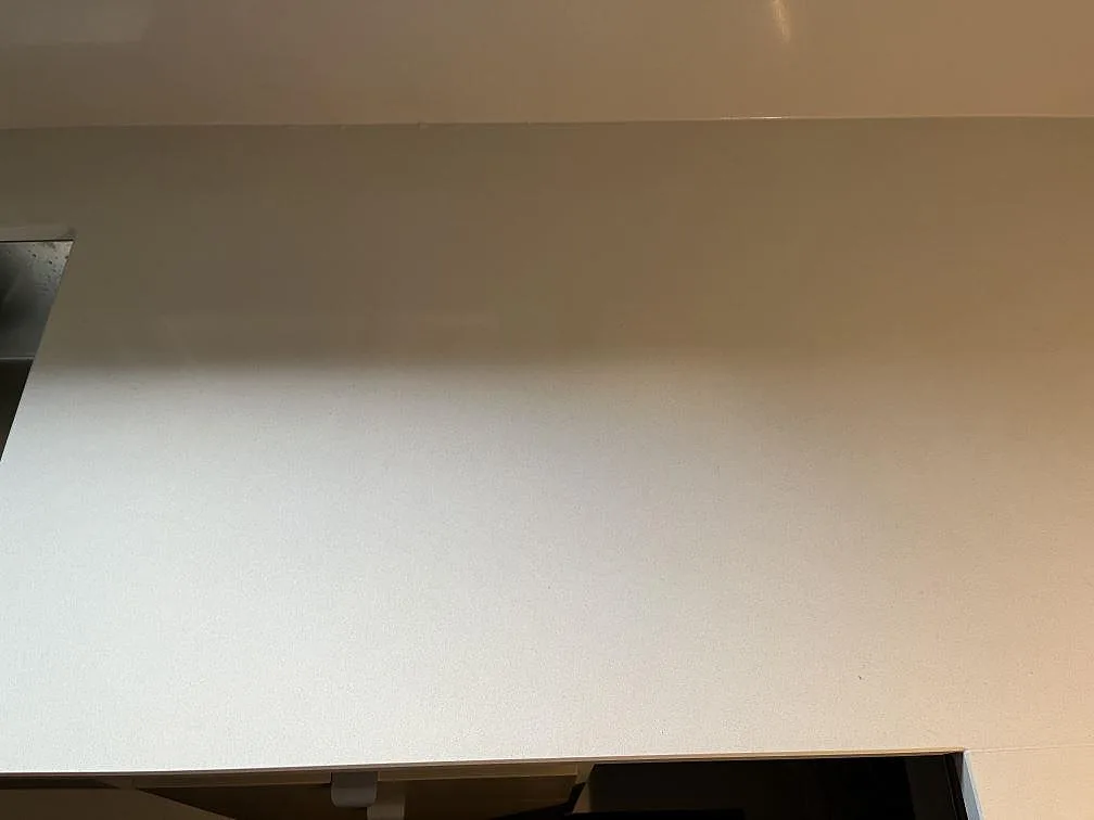 Närbild på den polerade ytan av en vit Quarella Blanco Sal kvartskompositbänk i ett kök i Tjörnarp.